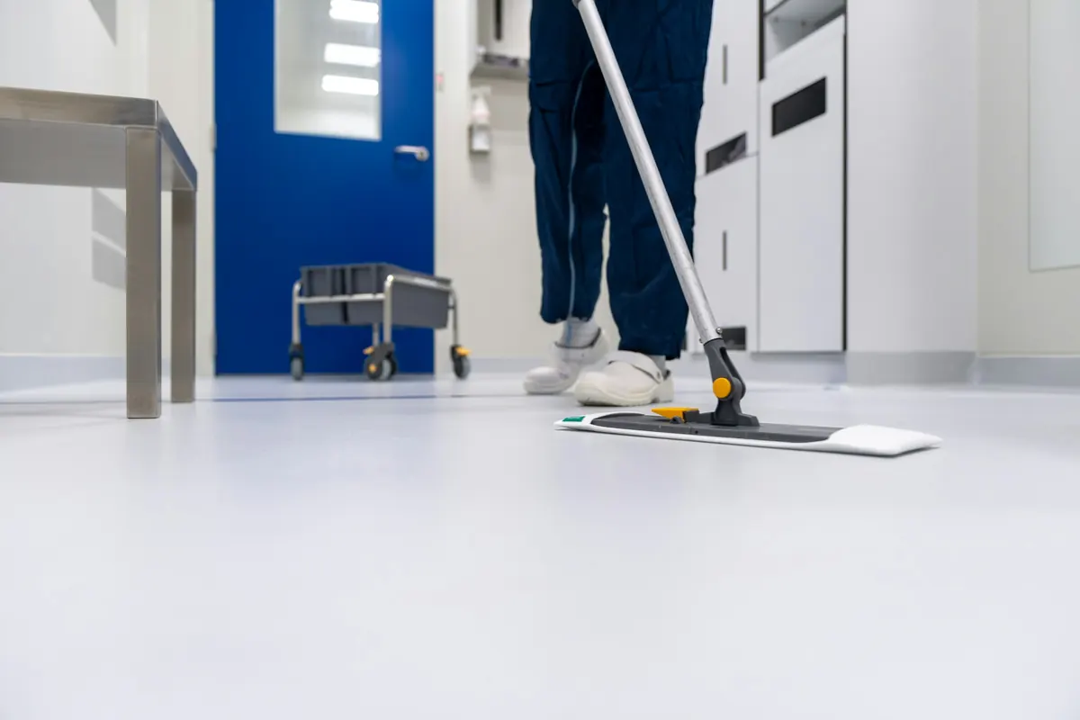 Profissional uniformizado limpando o piso de um ambiente corporativo